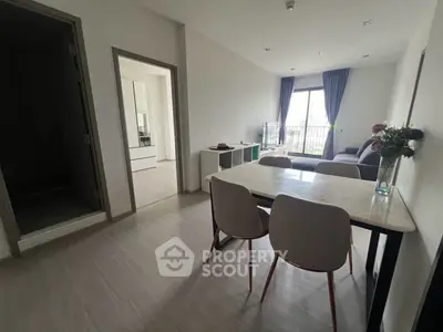 Modern dining area with elegant table and chairs, adjacent to a cozy living room with balcony view.