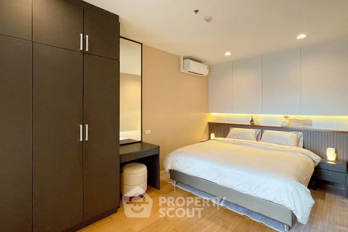 Modern bedroom with sleek wardrobe and cozy lighting in a stylish apartment.