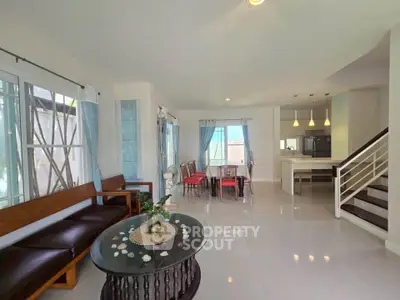 Spacious open-plan living and dining area with modern kitchen and elegant staircase.