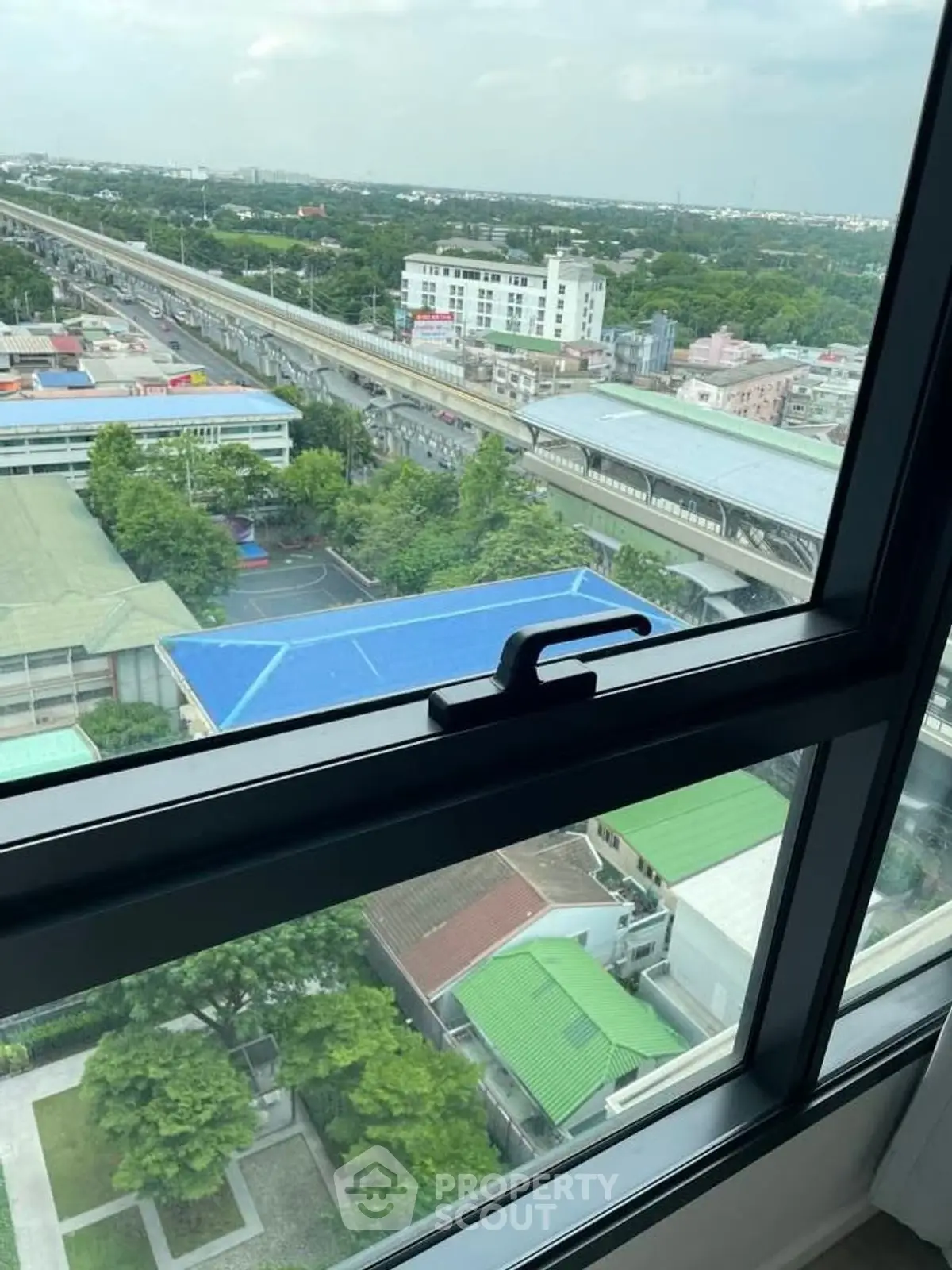 Stunning high-rise view from window overlooking cityscape and transit line.
