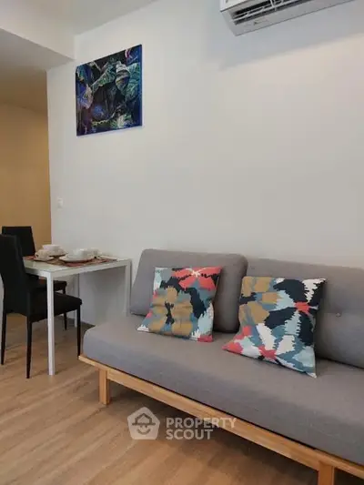 Modern living room with stylish sofa and dining area, featuring colorful cushions and contemporary decor.