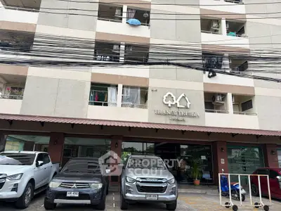 Modern apartment building exterior with parking area and multiple balconies.