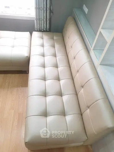 Modern beige leather sofa in a stylish living room with wooden flooring and natural light.