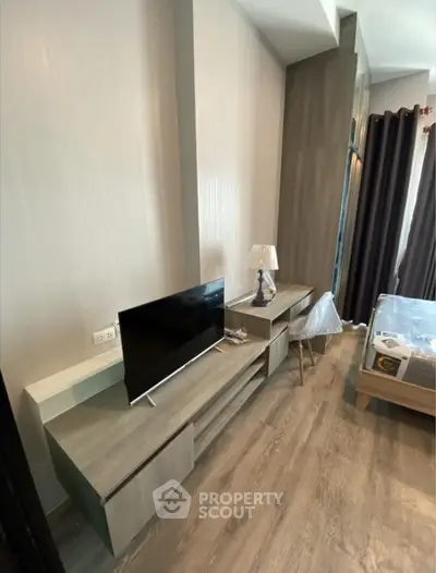 Modern bedroom with stylish furniture and TV unit, featuring elegant wood flooring and natural light.