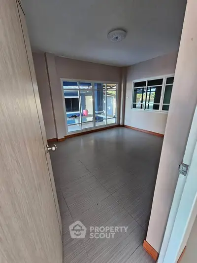 Spacious empty room with large windows and tiled flooring, perfect for customization.