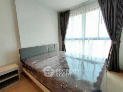 Spacious bedroom with large window and modern furnishings in a bright apartment.