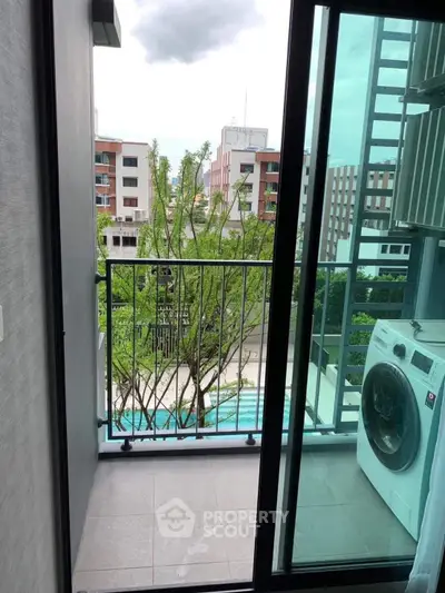 Modern balcony with washing machine and pool view in urban setting.