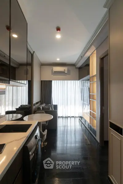 Modern living room with sleek design, featuring a cozy sofa, large windows, and integrated kitchen appliances.