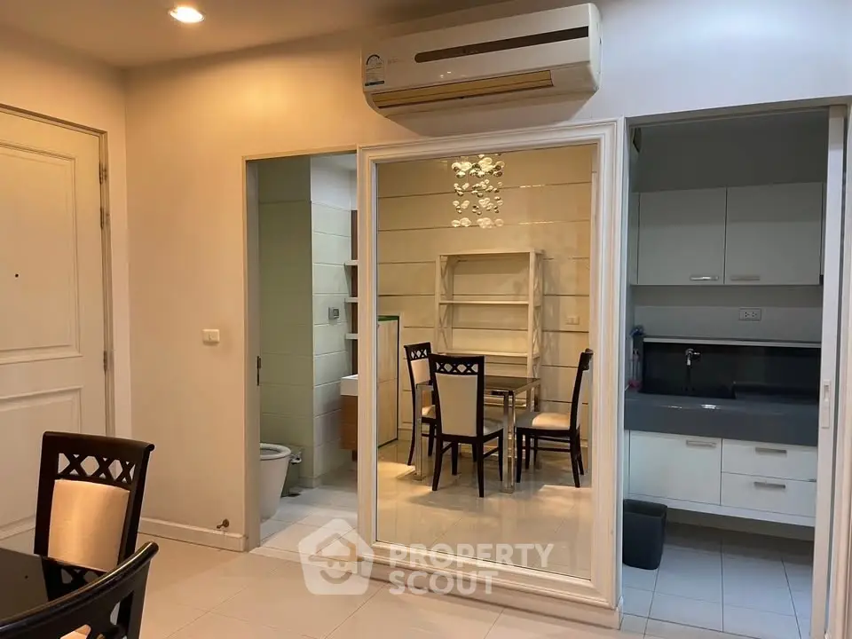 Modern apartment interior with dining area, kitchen, and bathroom view, featuring sleek design and air conditioning.