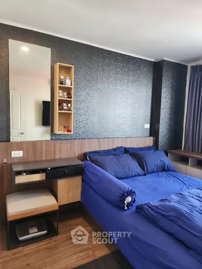 Modern bedroom with stylish decor and blue bedding in a contemporary apartment.