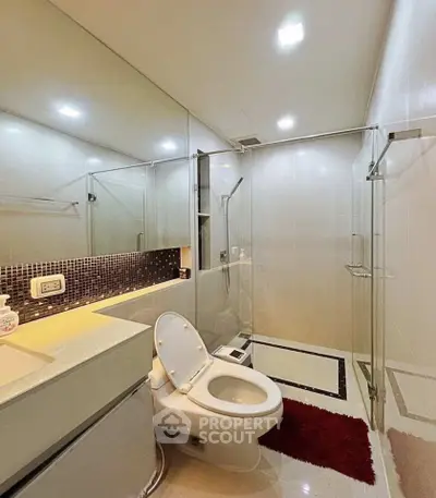 Modern bathroom with glass shower and sleek fixtures in a contemporary apartment.