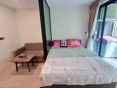 Cozy bedroom with sliding glass partition and small sofa, perfect for compact living.