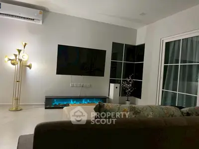 Modern living room with stylish decor, featuring a wall-mounted TV and elegant lighting.