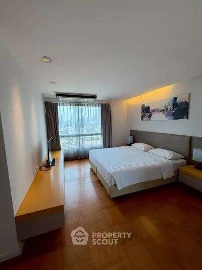 Spacious bedroom with large window offering stunning city views, modern decor, and elegant wooden flooring.