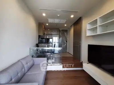 Modern living room with sleek design and open kitchen layout, featuring a cozy sofa and wall-mounted TV.