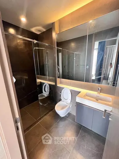 Modern bathroom with sleek design, glass shower, and wall-mounted toilet in luxury apartment.
