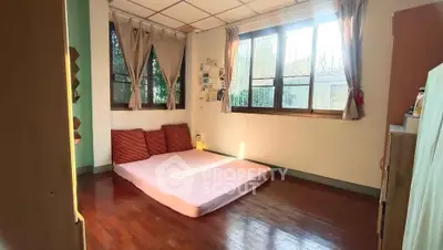 Cozy bedroom with large windows and wooden flooring, perfect for natural light lovers.