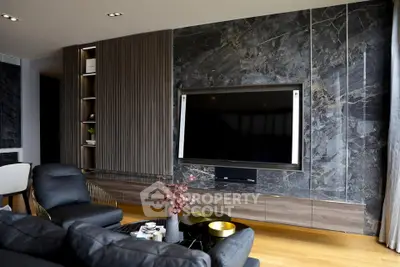 Luxurious living room with modern decor and large flat-screen TV, featuring elegant marble wall accents.