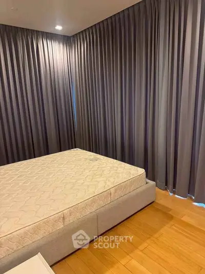 Spacious bedroom with elegant floor-to-ceiling curtains and a comfortable bed, perfect for relaxation.