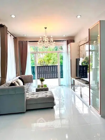 Luxurious living room with elegant chandelier and large windows overlooking a lush garden.