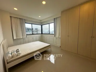 Spacious bedroom with large windows and built-in wardrobe offering city views.