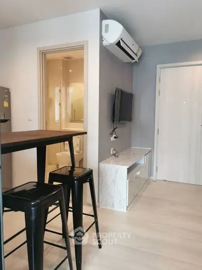 Modern apartment interior with sleek design, featuring a compact living area and visible bathroom entrance.