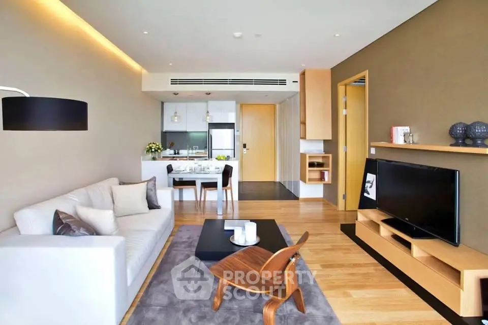 Modern living room with open kitchen, stylish furniture, and wooden flooring in a contemporary apartment.