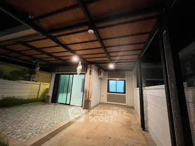 Modern covered patio with stylish lighting and sliding glass doors leading to the interior.
