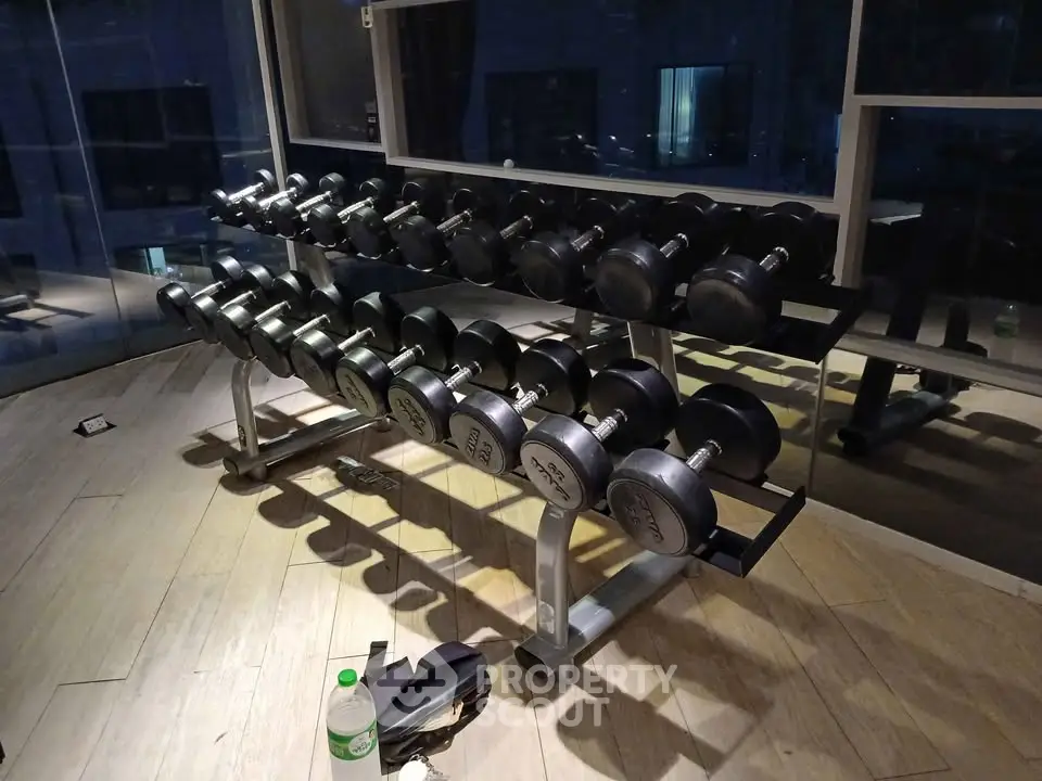 Modern gym with dumbbell rack and mirrored wall in luxury apartment complex