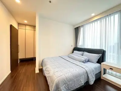 Spacious bedroom with modern decor and large windows for natural light.
