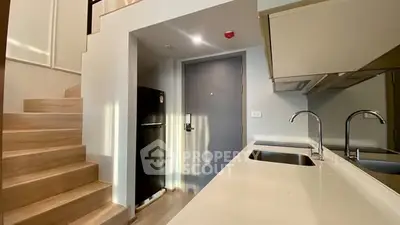 Modern kitchen with sleek countertops and staircase in stylish apartment