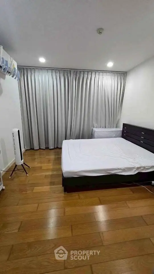 Spacious bedroom with wooden flooring and modern furnishings in a stylish apartment.