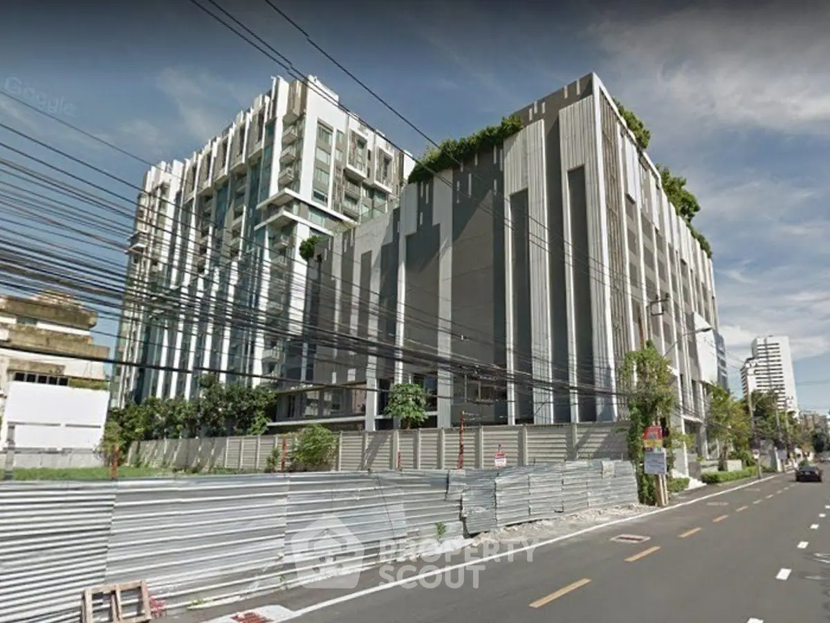 Modern urban building exterior with lush greenery and contemporary design on a sunny day.