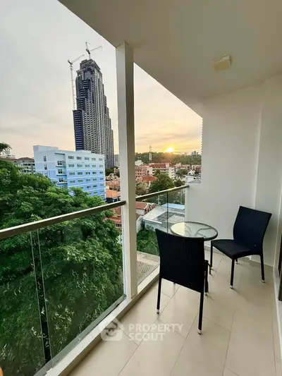 Modern balcony with stunning city view and cozy seating area at sunset.