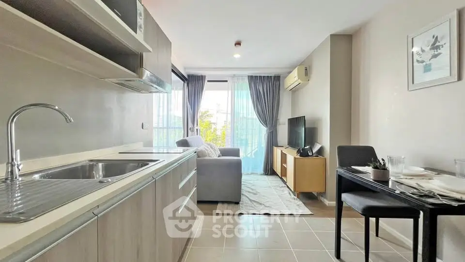 Modern open-layout living room with kitchen, featuring sleek furniture and natural light.