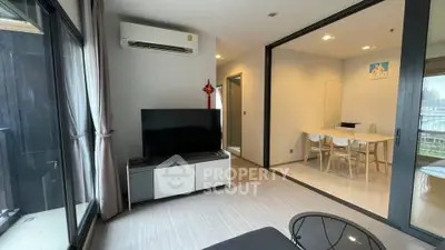 Modern living room with sleek furniture and dining area, featuring large windows and air conditioning.