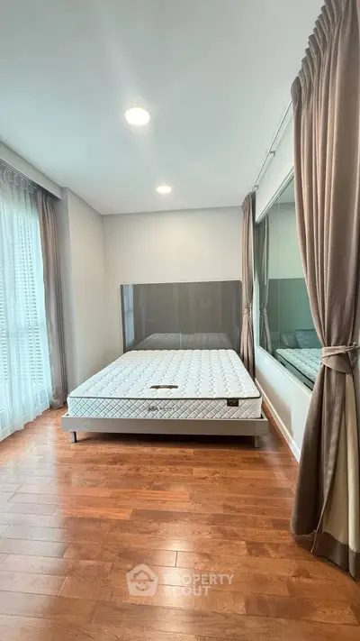 Spacious bedroom with hardwood floors and large window for natural light