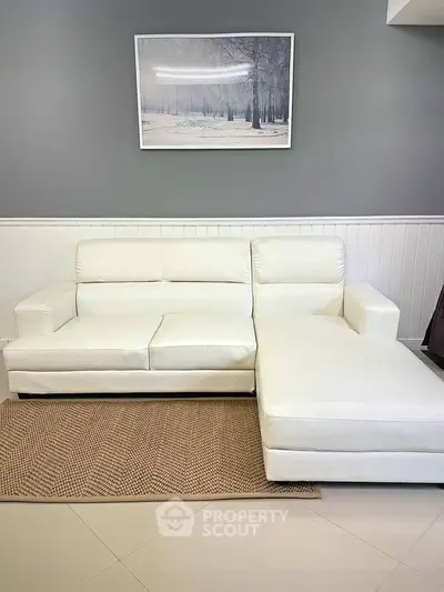 Modern living room with elegant white leather sofa and stylish decor.