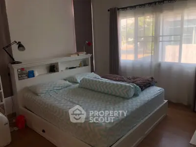 Cozy bedroom with large window and stylish decor, perfect for relaxation and comfort.