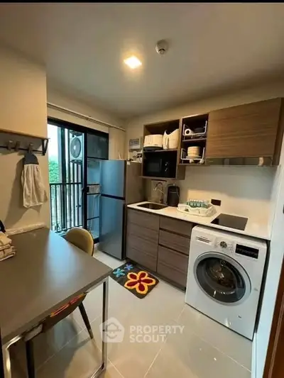 Modern kitchen with washing machine and balcony view, featuring sleek cabinetry and appliances.