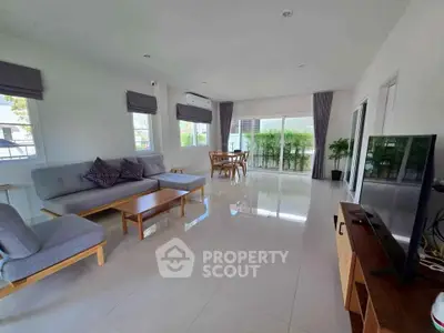Spacious modern living room with sleek furniture and large windows offering natural light.