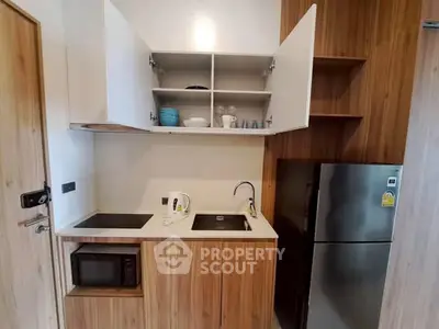 Modern compact kitchen with wooden cabinets and stainless steel appliances