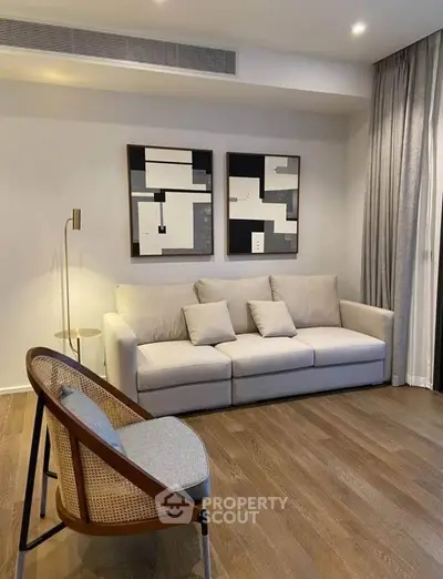 Modern living room with stylish furniture and abstract art, featuring a cozy sofa and elegant wooden flooring.