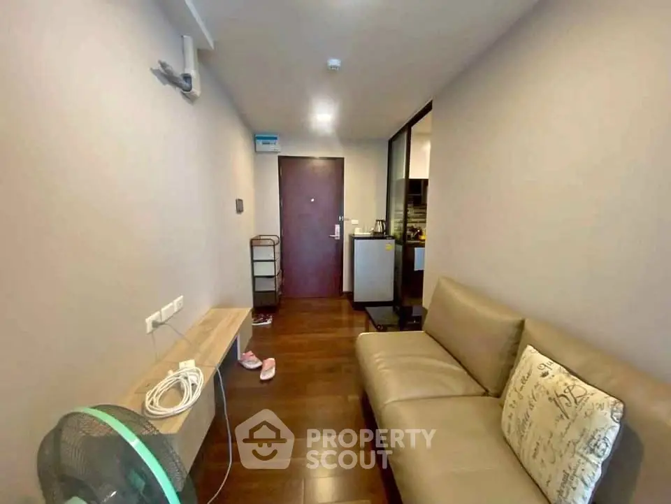 Cozy living room with modern sofa and wooden flooring in a compact apartment.