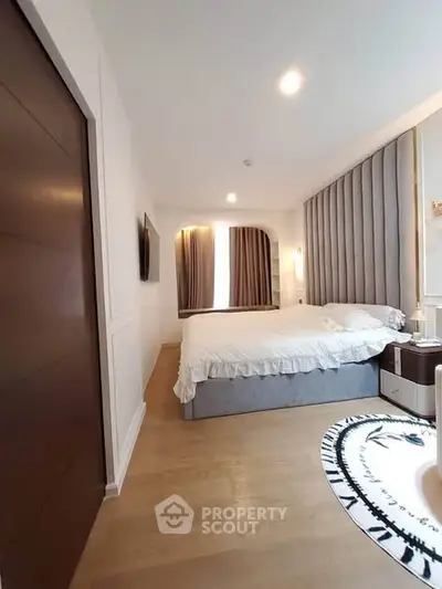 Modern bedroom with elegant decor and cozy lighting, featuring a plush bed and stylish wooden flooring.