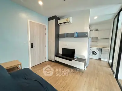 Modern living room with sleek furniture and open kitchen layout featuring a washing machine.