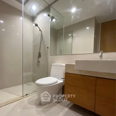 Modern bathroom with glass shower and sleek vanity in contemporary apartment.