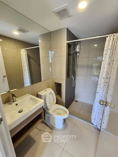 Modern bathroom with sleek fixtures and spacious shower area in contemporary apartment.