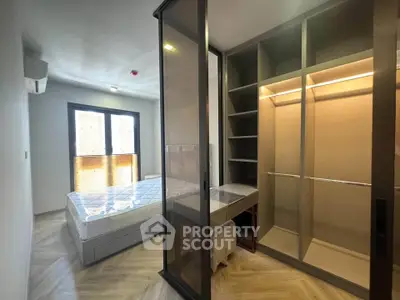 Modern bedroom with walk-in closet and large window, featuring sleek design and ample natural light.