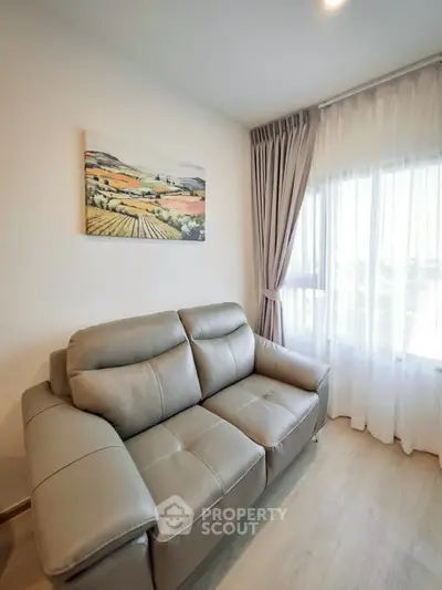 Modern living room with elegant sofa and scenic artwork, featuring natural light through large windows.